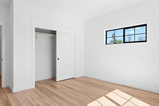 unfurnished bedroom featuring a closet, light wood-style flooring, and baseboards