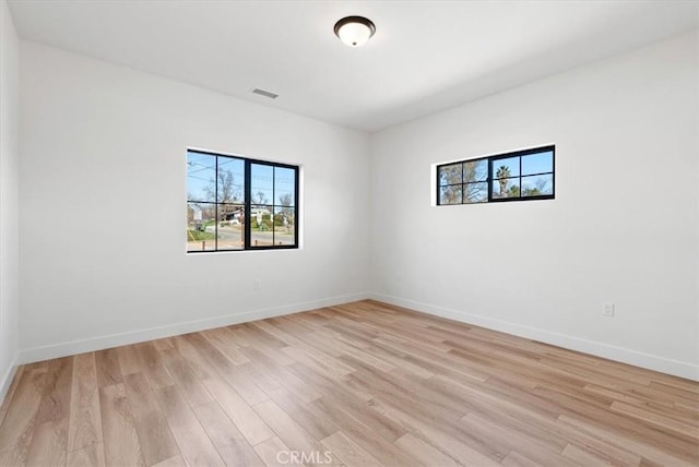 spare room with light wood-style floors, visible vents, and baseboards