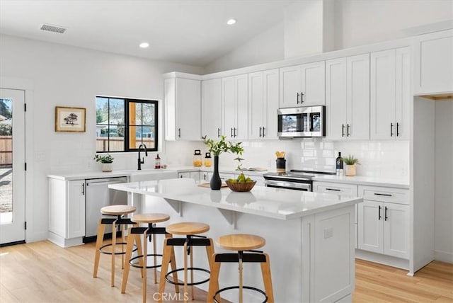 kitchen with visible vents, a kitchen island, white cabinetry, appliances with stainless steel finishes, and light countertops