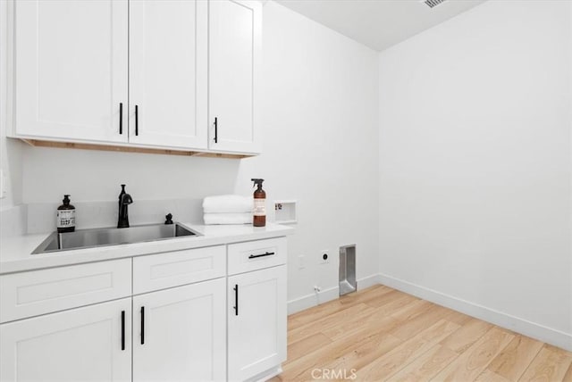 washroom with washer hookup, light wood-style flooring, cabinet space, hookup for an electric dryer, and a sink