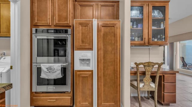 kitchen with dark stone counters, a healthy amount of sunlight, light tile patterned floors, and stainless steel double oven