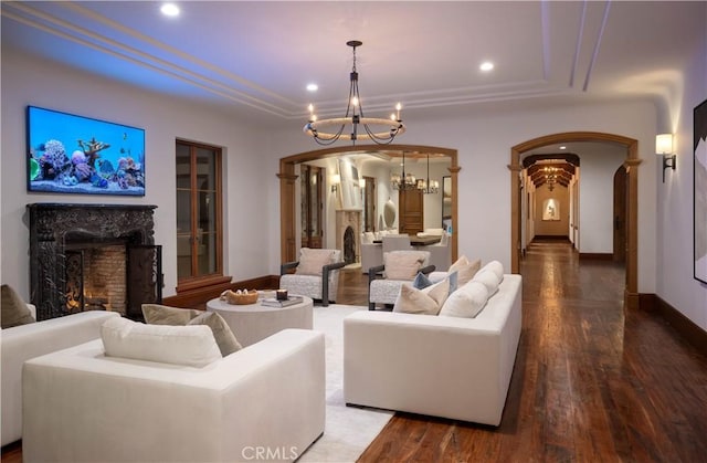 living room with a high end fireplace, hardwood / wood-style floors, a tray ceiling, and an inviting chandelier