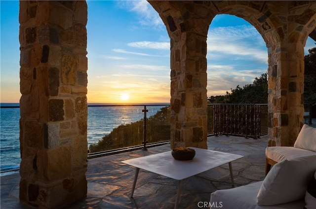 patio terrace at dusk featuring a water view