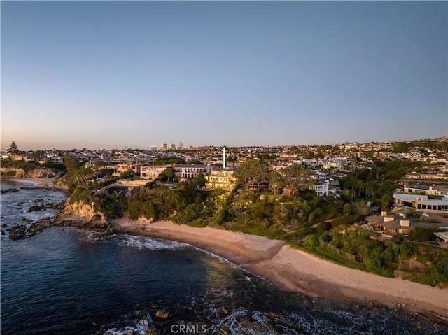 aerial view at dusk featuring a view of the beach and a water view