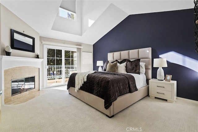 carpeted bedroom featuring access to exterior, a tile fireplace, and vaulted ceiling