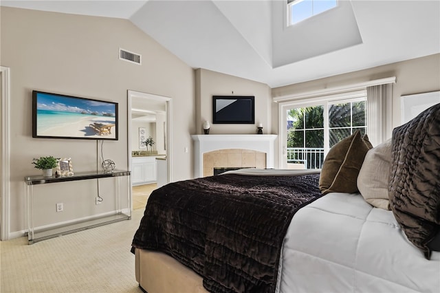 carpeted bedroom featuring ensuite bathroom, vaulted ceiling, and a tiled fireplace