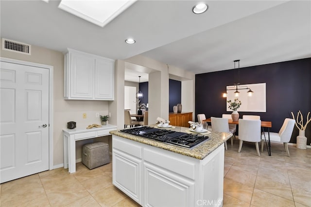 kitchen with a center island, a notable chandelier, decorative light fixtures, stainless steel gas stovetop, and white cabinets