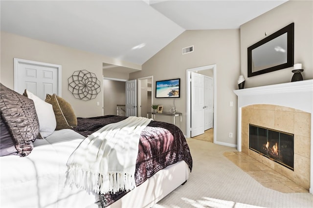 carpeted bedroom with a tiled fireplace and lofted ceiling