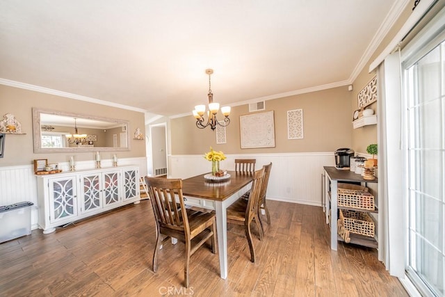 dining area featuring hardwood / wood-style floors, crown molding, and an inviting chandelier