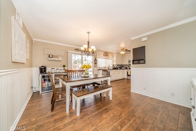 dining space featuring hardwood / wood-style floors, ceiling fan with notable chandelier, ornamental molding, and sink