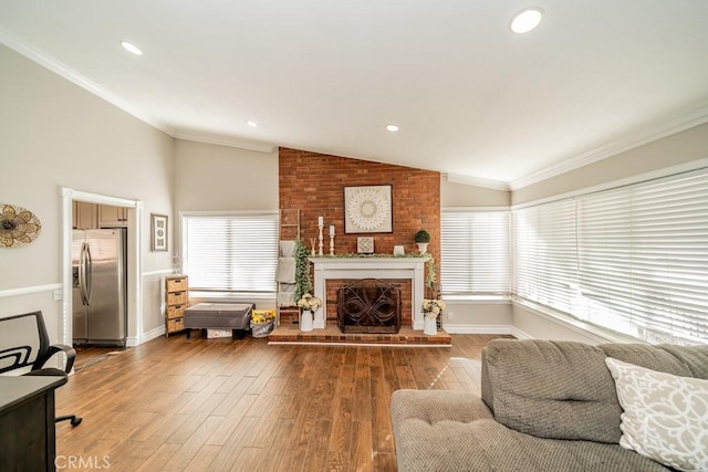 living room with a fireplace, wood-type flooring, vaulted ceiling, and crown molding