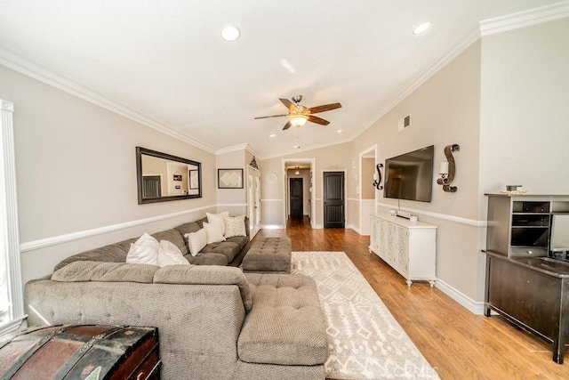 living room with lofted ceiling, ceiling fan, ornamental molding, and light hardwood / wood-style flooring