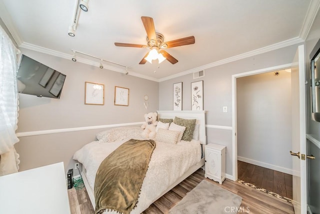 bedroom with hardwood / wood-style floors, rail lighting, ceiling fan, and ornamental molding