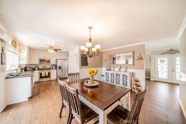 dining room featuring plenty of natural light, light hardwood / wood-style floors, ornamental molding, and ceiling fan with notable chandelier