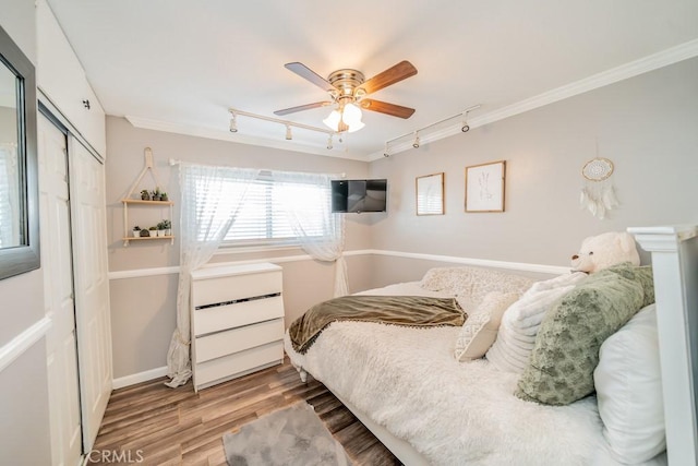 bedroom with track lighting, crown molding, ceiling fan, light hardwood / wood-style floors, and a closet