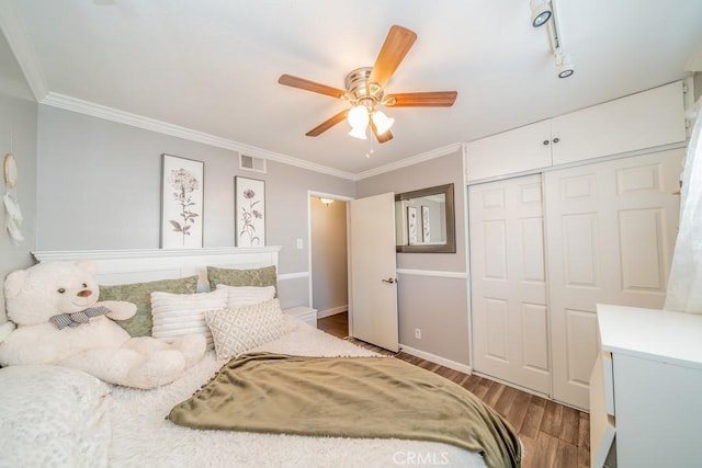 bedroom featuring crown molding, rail lighting, light hardwood / wood-style flooring, ceiling fan, and a closet