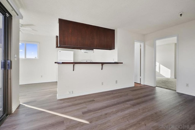 unfurnished living room with ceiling fan, wood-type flooring, and a textured ceiling