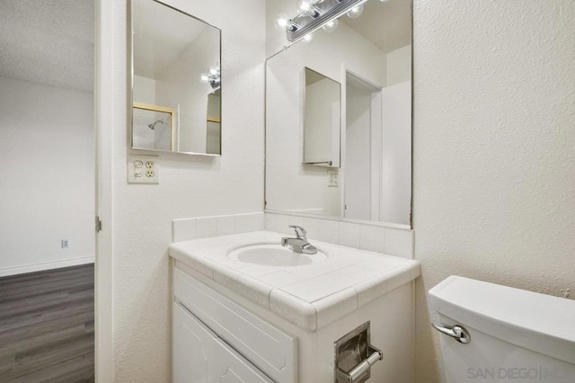 bathroom featuring hardwood / wood-style floors, vanity, toilet, and a textured ceiling