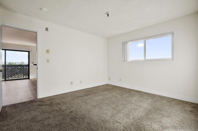 carpeted spare room with plenty of natural light and a textured ceiling