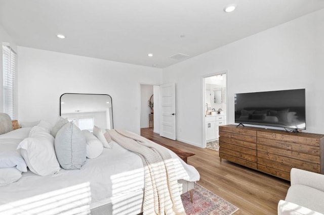 bedroom featuring connected bathroom and light wood-type flooring