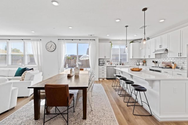 dining space featuring sink, light wood-type flooring, and a wealth of natural light