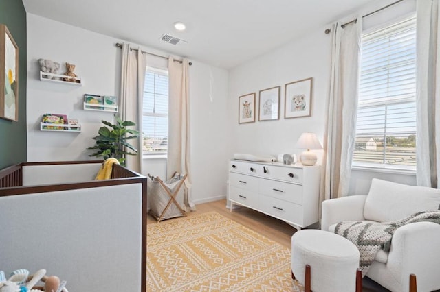 bedroom with light hardwood / wood-style floors and a nursery area