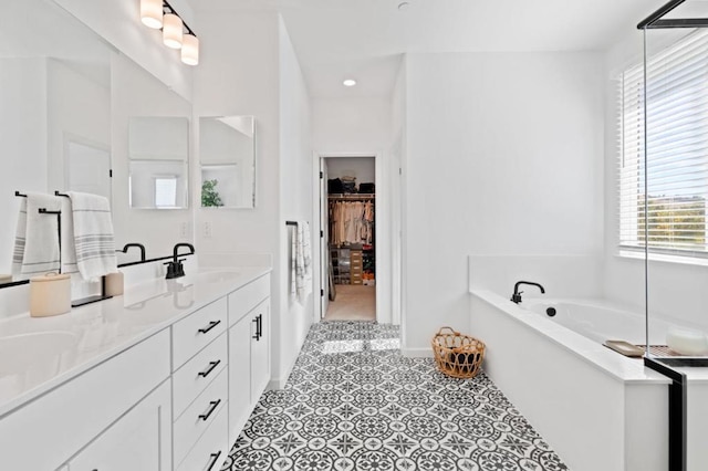 bathroom featuring tile patterned flooring, a healthy amount of sunlight, a bathtub, and vanity