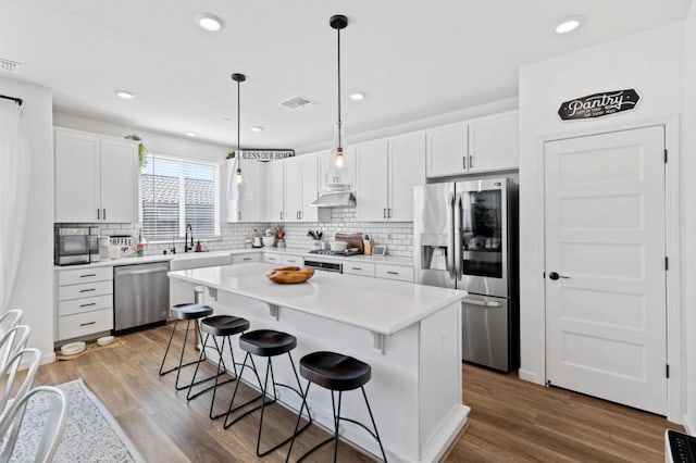 kitchen featuring white cabinets, pendant lighting, stainless steel appliances, and a center island