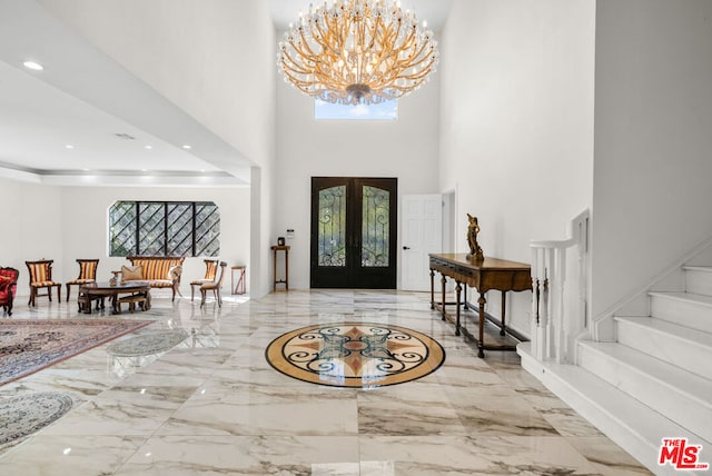 entryway with a towering ceiling, french doors, and a chandelier