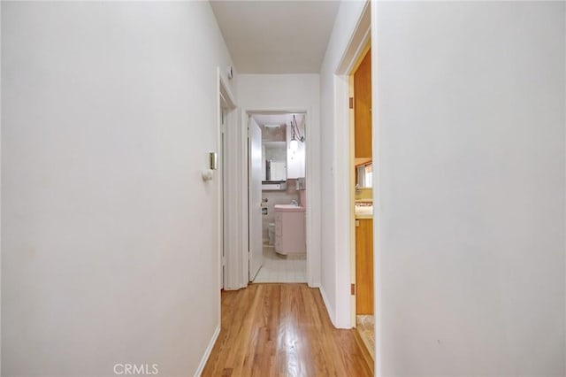 corridor with light hardwood / wood-style flooring and sink