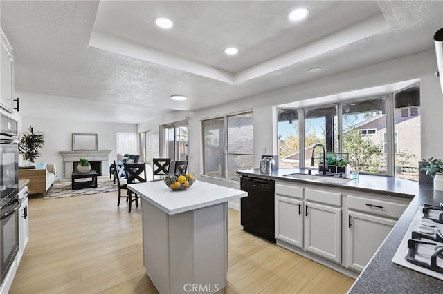 kitchen with black appliances, white cabinetry, sink, and a tray ceiling