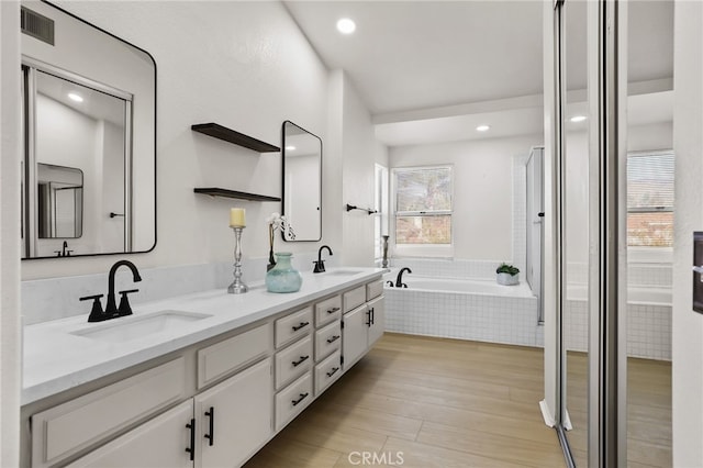 bathroom with vanity, a relaxing tiled tub, and hardwood / wood-style flooring