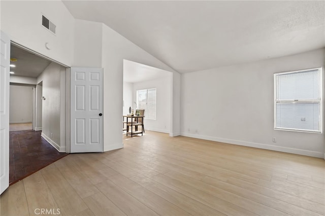 spare room with lofted ceiling and light wood-type flooring