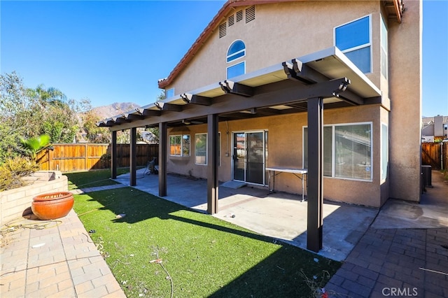 back of property with a mountain view, a yard, and a patio