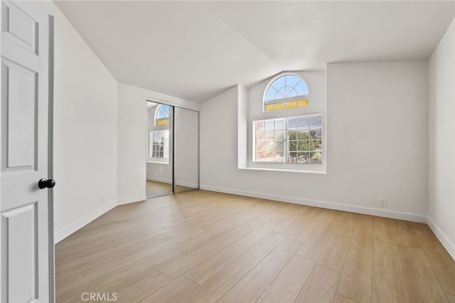 spare room with light hardwood / wood-style floors and vaulted ceiling