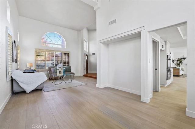 sitting room with a high ceiling and light hardwood / wood-style floors