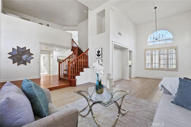 living room featuring light wood-type flooring, high vaulted ceiling, and an inviting chandelier