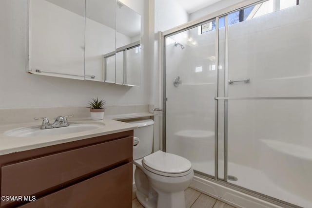 bathroom featuring vanity, an enclosed shower, and toilet