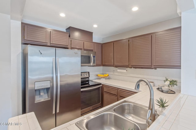 kitchen featuring tile countertops, sink, and stainless steel appliances