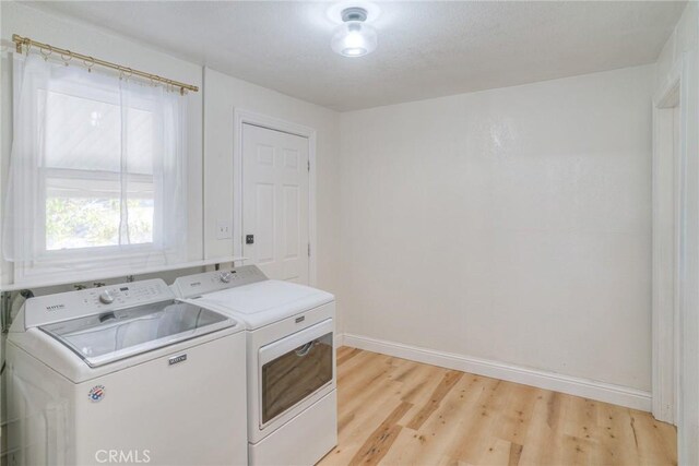 laundry area featuring independent washer and dryer, a textured ceiling, and light hardwood / wood-style flooring