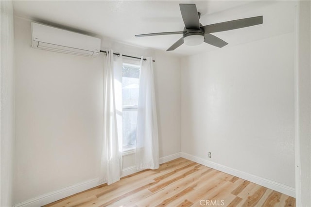 spare room with light wood-type flooring, an AC wall unit, and ceiling fan