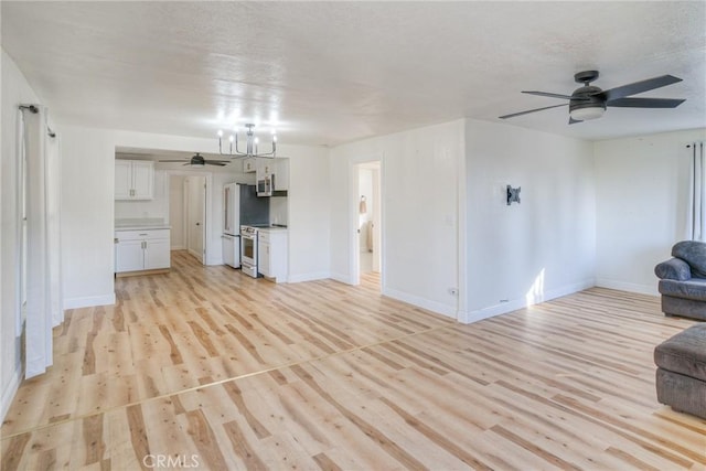 unfurnished living room with a textured ceiling, light wood-type flooring, and an inviting chandelier