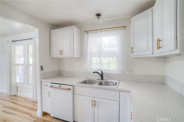 kitchen with white dishwasher, a healthy amount of sunlight, white cabinets, and sink