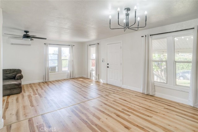 foyer entrance with ceiling fan with notable chandelier, a textured ceiling, light wood-type flooring, and a wall unit AC