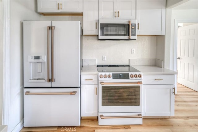 kitchen with white cabinets, white appliances, and light hardwood / wood-style floors