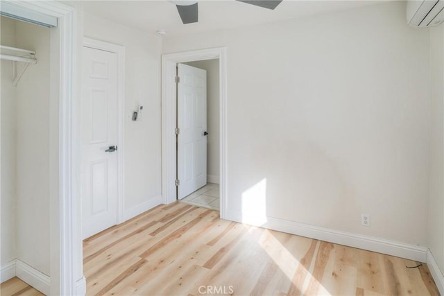 unfurnished bedroom with a closet, light hardwood / wood-style flooring, a wall mounted AC, and ceiling fan