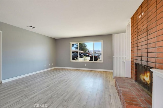 unfurnished living room featuring a fireplace and light hardwood / wood-style floors