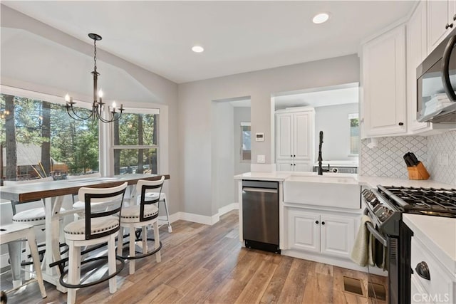 kitchen with white cabinets, a chandelier, sink, and stainless steel appliances