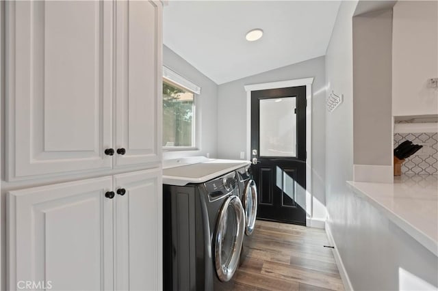 laundry room featuring cabinets, washer and clothes dryer, and light wood-type flooring