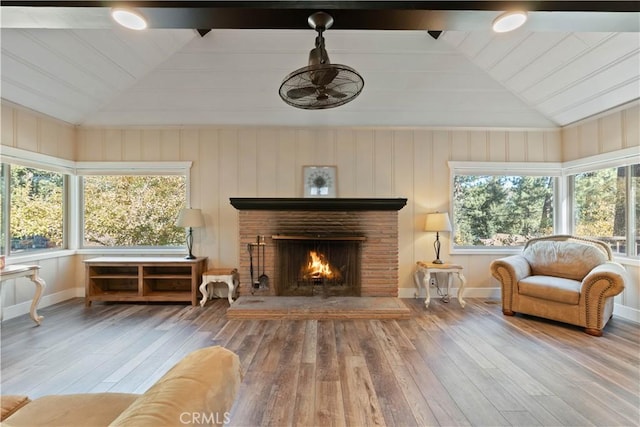 sunroom featuring ceiling fan, vaulted ceiling with beams, and a brick fireplace